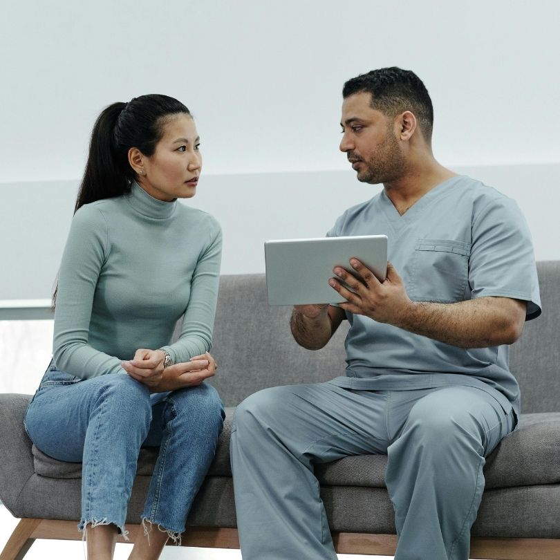 A psychiatric nurse practitioner writing notes on a medical evaluation form during a consultation.